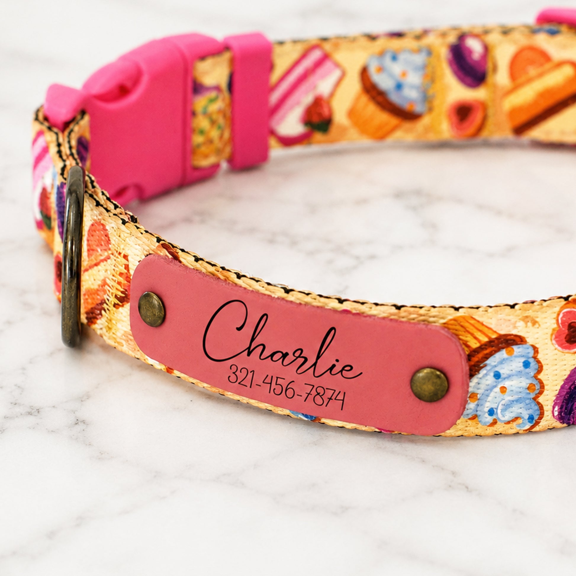 Colorful dog collar with a pink name tag on a marble surface