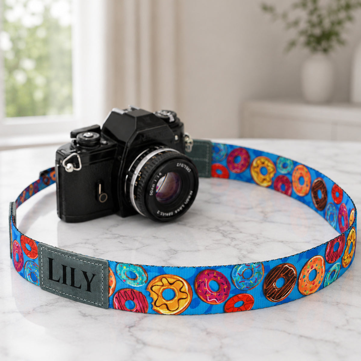 Camera with a colorful donut patterned strap on a marble surface