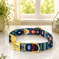 Colorful patterned dog collar with a gold tag on a light surface.
