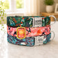 Three colorful dog collars stacked on a surface with visible names and tags.