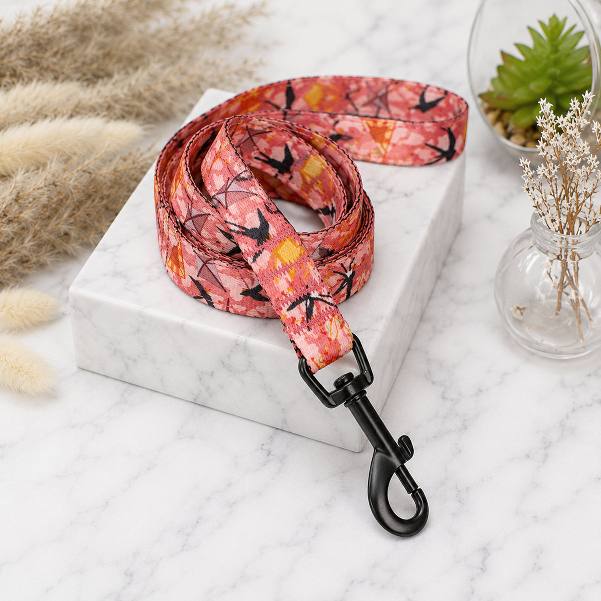 Pink floral patterned dog leash on a marble surface with decorative elements.