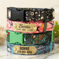 Three colorful dog collars with nameplates on a marble surface
