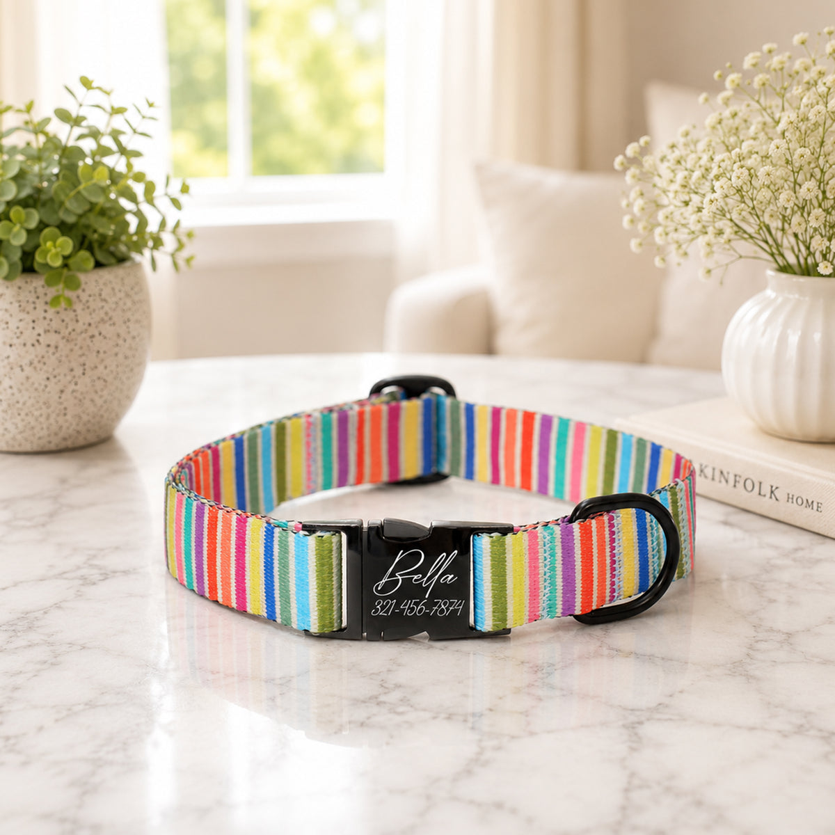 Colorful striped dog collar with a black buckle on a marble surface, with a blurred indoor background.