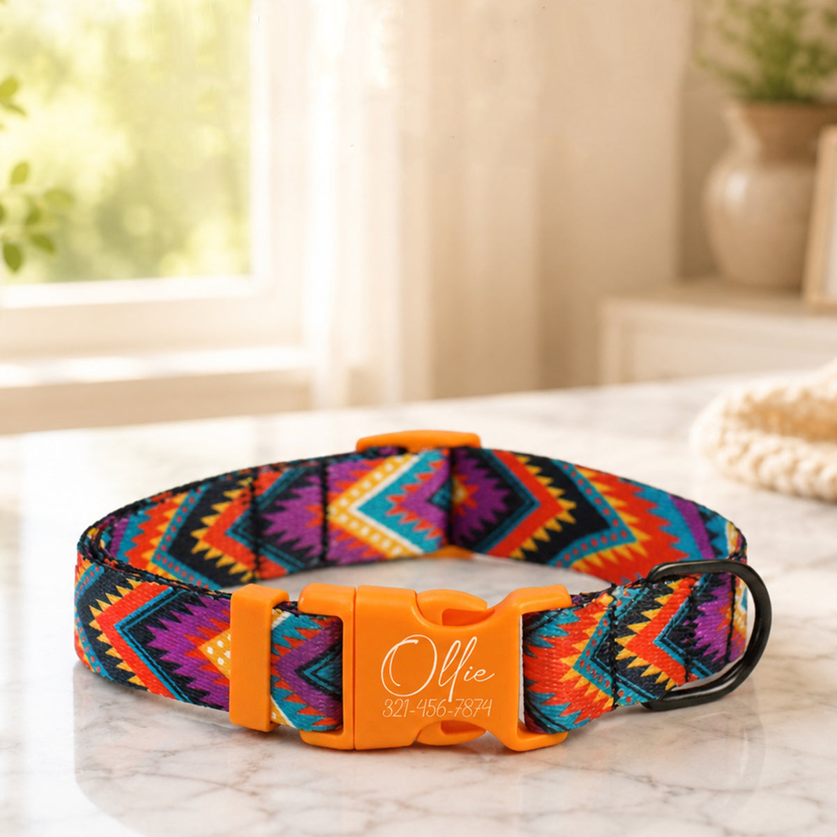 Colorful dog collar with a personalized orange buckle on a marble surface.