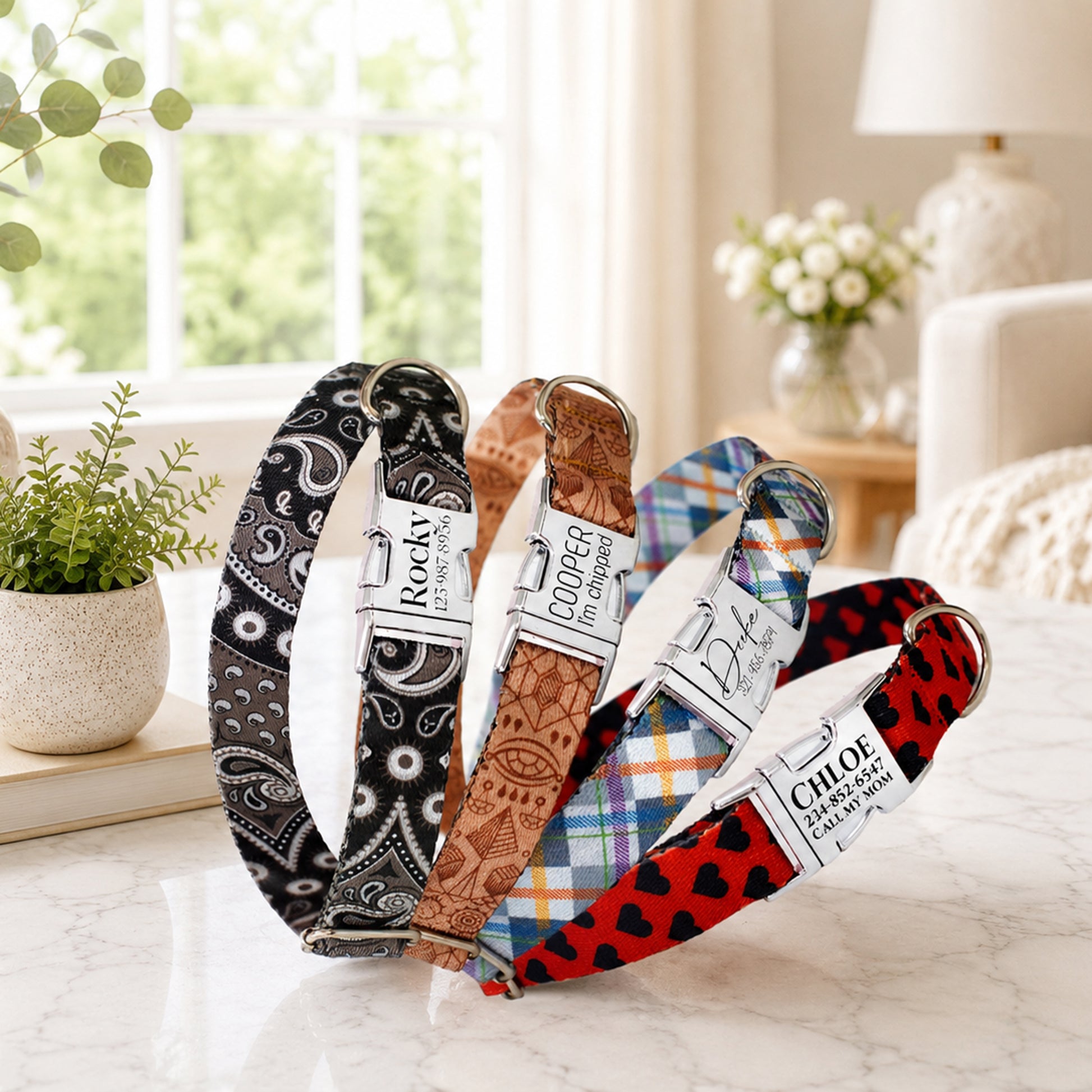 Four dog collars with different patterns and names on a marble surface.