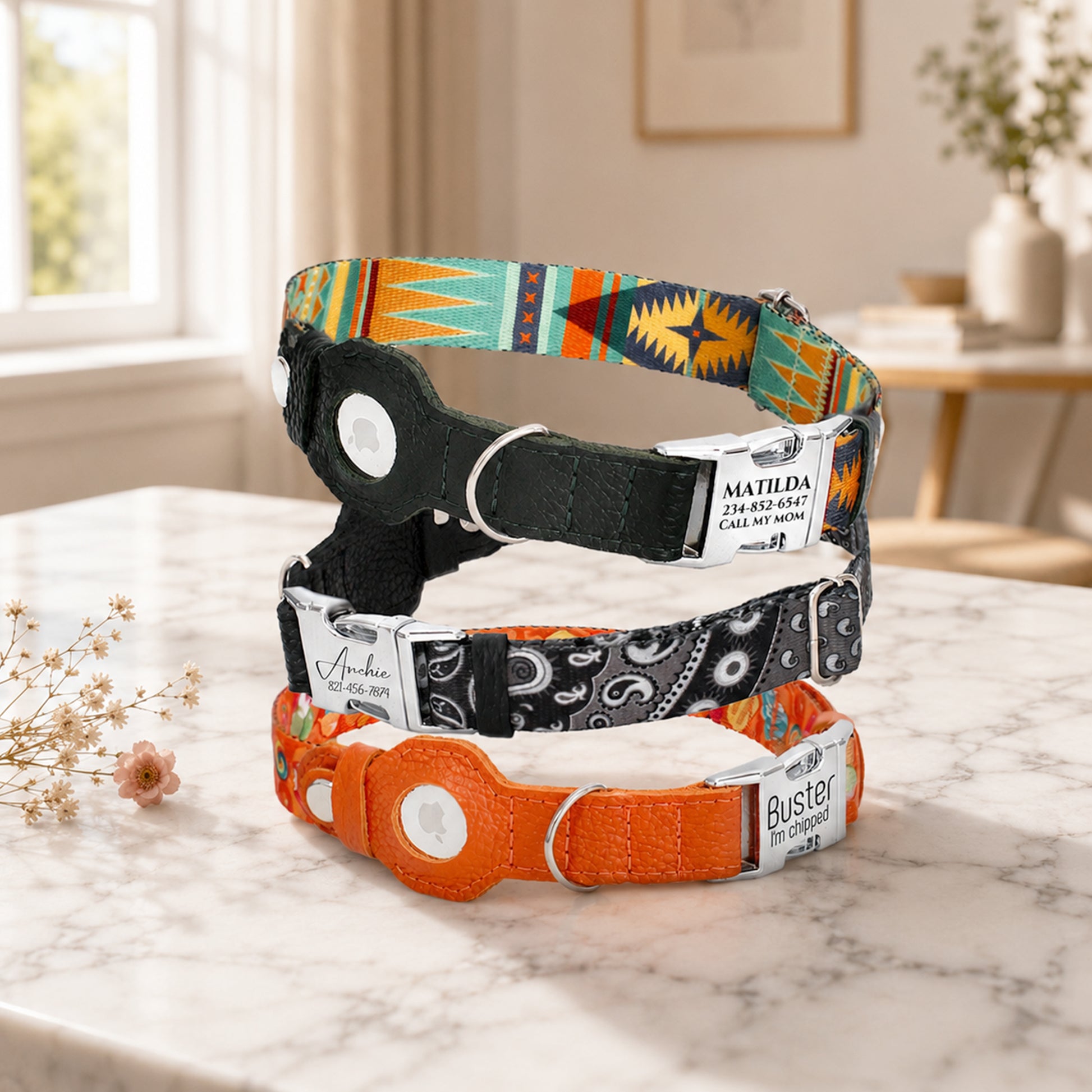 Three colorful dog collars with engraved names on a marble surface.