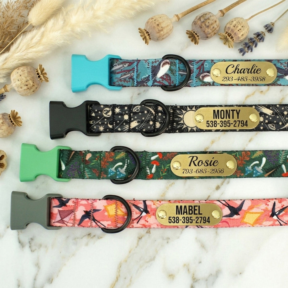Four colorful dog collars with nameplates on a marble surface.
