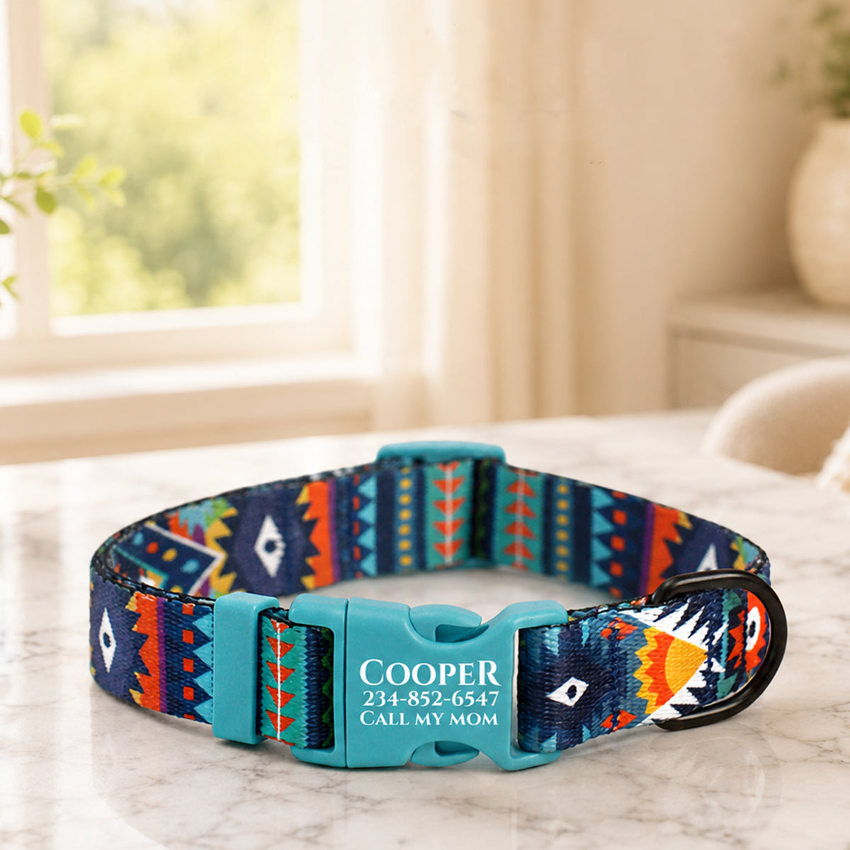 Colorful patterned dog collar with engraved text on a marble surface