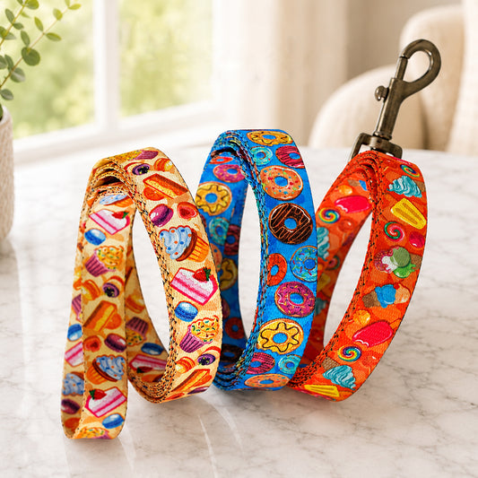 Three colorful dog leashes with candy-themed patterns on a marble surface.