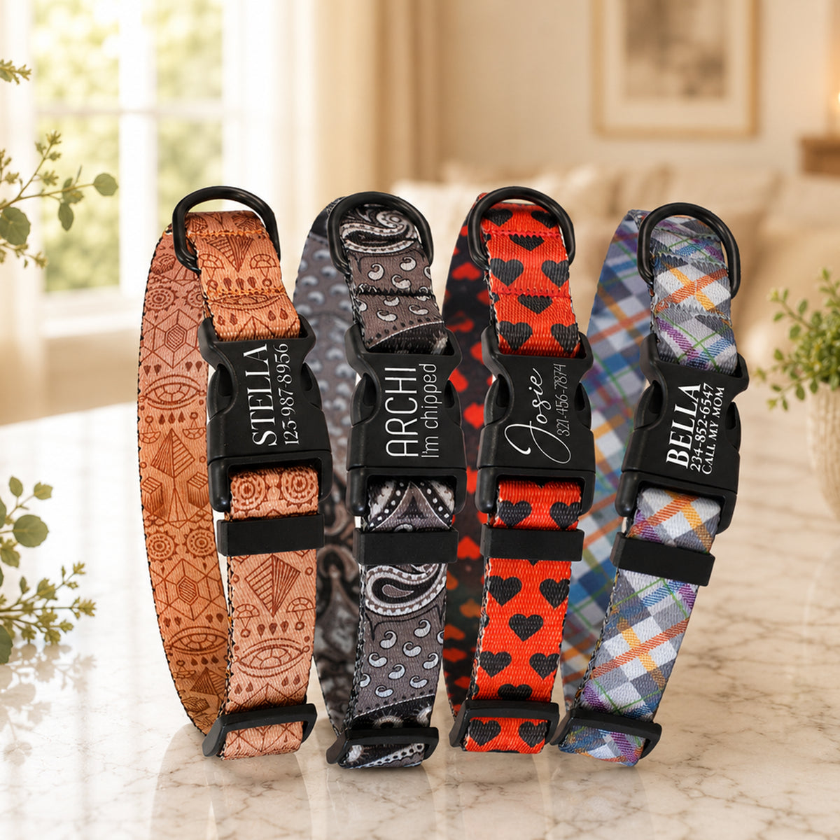 Four dog collars with different patterns and names engraved on them, placed on a marble surface.