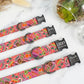 Colorful patterned pet collars with engraved names on a marble surface.