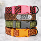 Stack of colorful dog collars with engraved nameplate on a marble surface