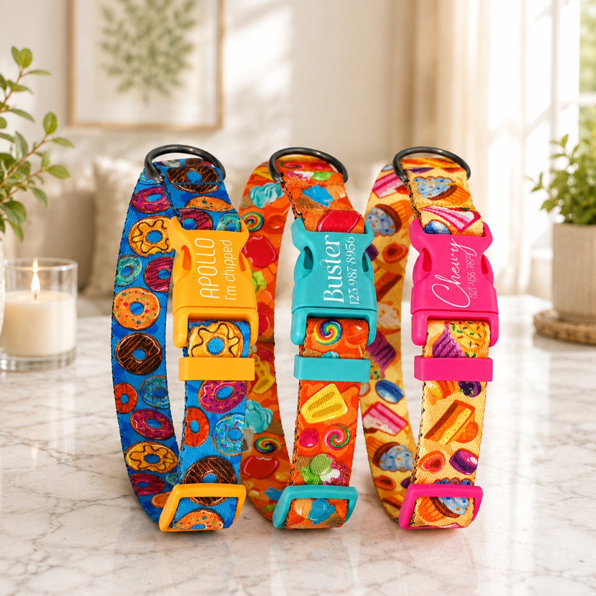 Three colorful dog collars with name tags on a marble surface.
