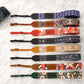 Collection of colorful camera straps with personalized names on a light background