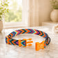 Colorful dog collar with orange clip on a marble surface