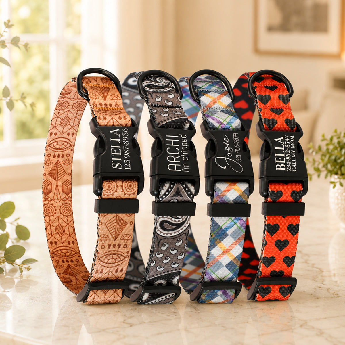 Five patterned pet collars with engraved names on a marble surface.