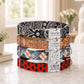 Stack of colorful dog collars with engraved names on a marble surface.