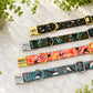 Three colorful dog collars with engraved names on a marble surface.