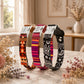 Three patterned dog collars on a marble surface with flowers and a window in the background