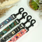 Set of colorful patterned leashes with black clasps on a white surface.