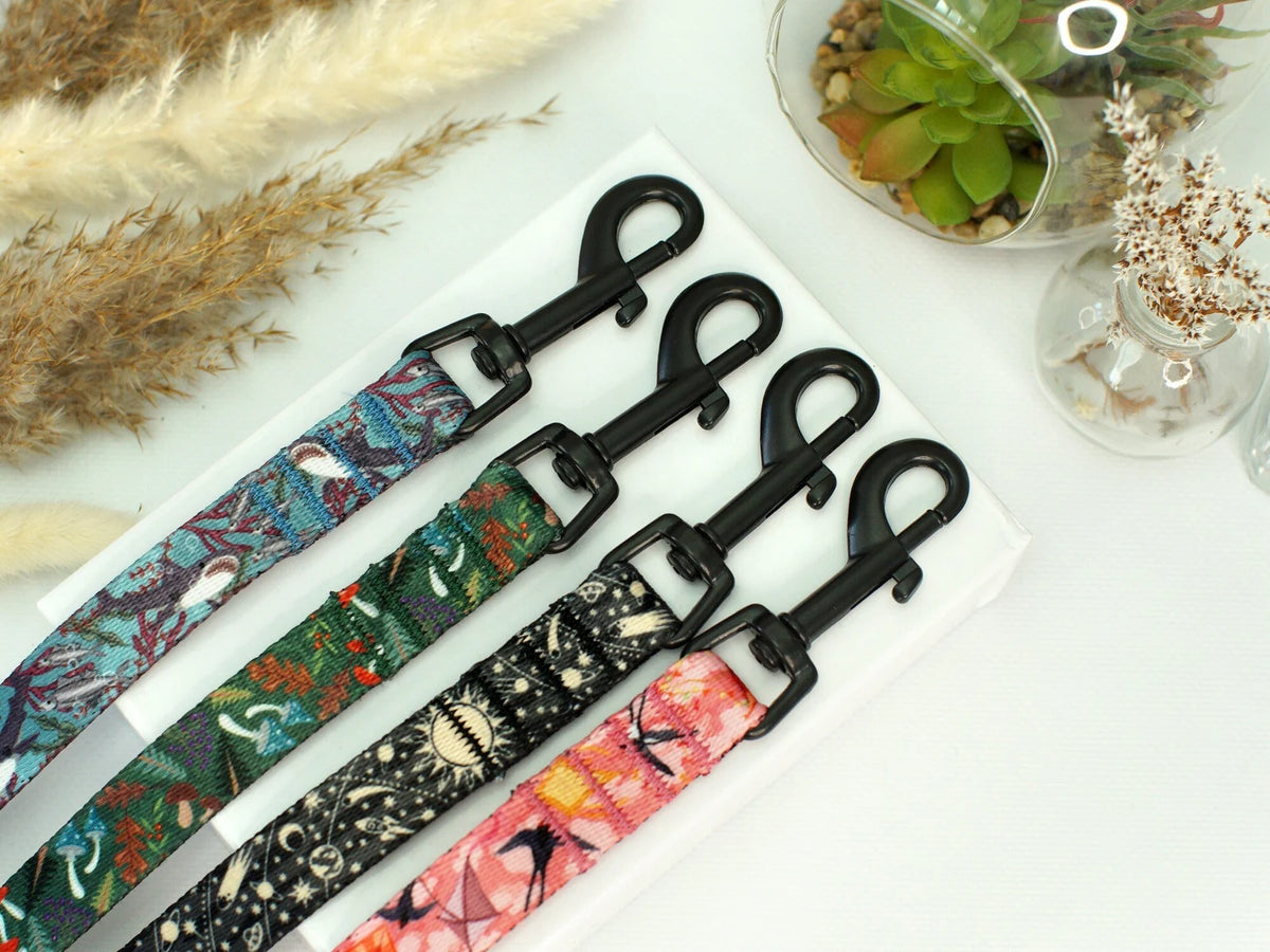 Set of colorful patterned leashes with black clasps on a white surface.