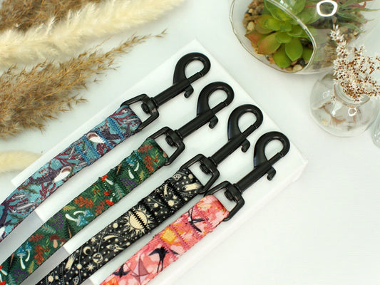 Set of colorful patterned leashes with black clasps on a white surface.